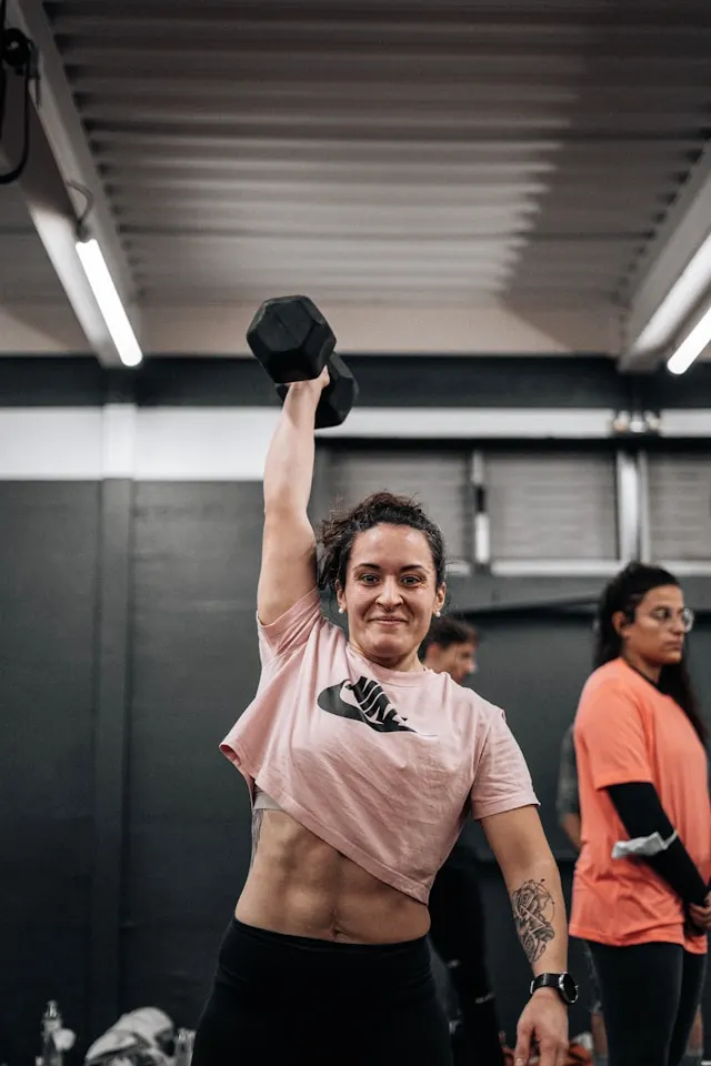 Femme sportive soulevant un poids de musculation dans une salle de sport pour faire du fitness et du crossfit